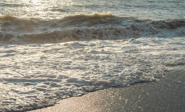 Günbatımının ışınlarında denizde fırtına büyük dalgalar, sprey