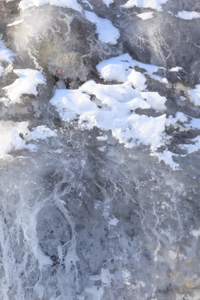 Лед течет по камню на берегу зимнего озера — стоковое фото