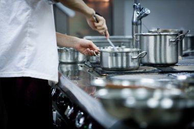 Şef veya aşçı ticari Restoran mutfağında yemek hazırlanırken bir yapışmaz tavada et gaz hob üzerinde salata soslarında