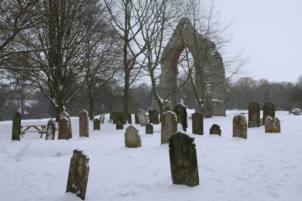Wymondham Manastırı 'nın tarihi yıkıntılarının kar manzarası Norfolk Doğu Anglia İngiltere' deki antik dini binanın bir parçası. Buz gibi soğuk kar fırtınasının ardından buz gibi kar yağışı, mezarlık ve mezar taşlarının üzerinde kış mevsiminde donmuş hava koşulları.