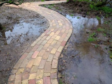 Sel basmış bahçe yolunun kapatılması eski ev tuğlalarından yeni inşa edildi ve taşkın suları ile kıvrımlı şeritler oluşturmak için sert zemine serildi. Islak toprak ve ağır kil toprak yüzeyinde kurumuş havuzlar oluşturdu.