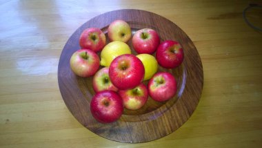 Olgun kırmızı elmalara yakın, bahçedeki İngiliz ağacından taze toplanmış organik, lezzetli meyveler ve yazın mutfak yüzeyinde ahşap tabaklar.