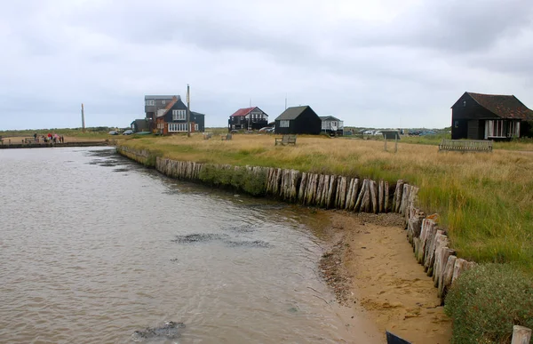 Blyth nehrinin manzarası Suffolk Doğu Anglia limanından geçen Walberswick haliç feribotu tarihi binalar yeşil kara ve fırtınalı yaz gökyüzü ile açık denize bakıyor.