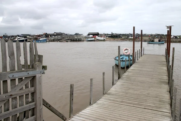 Walberswick 'ten Southwold, Suffolk, Doğu Anglia' ya kadar Blyth nehri boyunca demirleyen feribot platformunun manzarası. Limandaki yüksek gelgitte yelkenli tekneler, gri su ve bulutlar.
