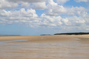 Norfolk, Holkham 'daki engin kumlu plajın güzel manzarası. Doğu Anglia' da yaz tatilinde mavi gökyüzünde beyaz kabarık bulutlar.