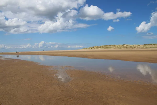 人も砂もない美しい砂浜の風景が水平線に伸び ホルカム北部のウォータープールに白いパフィーの雲が反映されています East Anglia — ストック写真