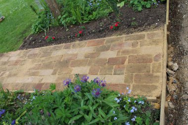 Tuğla yolu inşaatını kapatın. Tuğladan yapılma antika ev krem tuğlaları. Baharda güneş ışığı altında seraya ve çimlere uzanan düz bir bahçe yolu yapmak için.