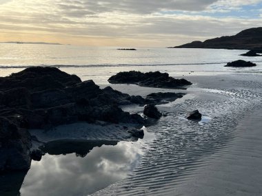 İskoçya 'nın güzel, vahşi kumsalı Uisken güzel kayalık ve kumlu sahil gündoğumu su havuzlarıyla güneş ışığını ufuktaki engin okyanusu vahşi yaşam ve kışın mavi gökyüzünü yansıtır.