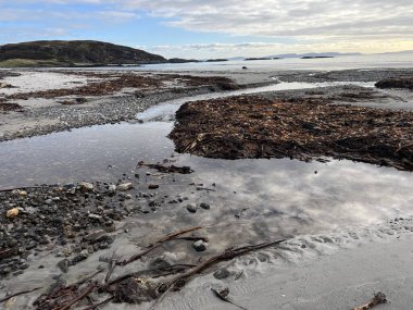 İskoçya 'nın güzel, vahşi kumsalı Uisken güzel kayalık ve kumlu sahil gündoğumu su havuzlarıyla güneş ışığını ufuktaki engin okyanusu vahşi yaşam ve kışın mavi gökyüzünü yansıtır.