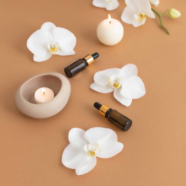 Temel aroma yağı, orkide çiçekleri ve mum ışığıyla çevrili.