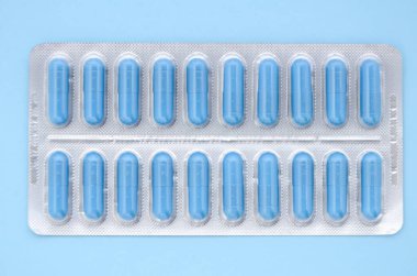 Mavi bir kapsülün içinde mavi bir arka planda fotokopi alanı olan mavi tıbbi kapsüller. Tıbbi düzlük.