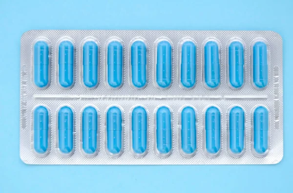 Mavi bir kapsülün içinde mavi bir arka planda fotokopi alanı olan mavi tıbbi kapsüller. Tıbbi düzlük.