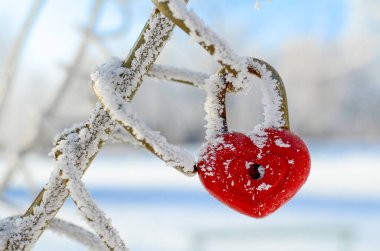 Kalp şeklinde buz tutmuş kırmızı asma kilit. Sevgililer Günü konsepti, düğünler. Kış arkaplanı, kopyalama alanı olan kart.