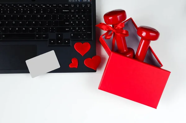 两个红色哑铃 带蝴蝶结在打开的红色盒子 笔记本电脑和心脏白色背景 情人节的概念 网上购物 健康的生活方式 热爱运动 — 图库照片