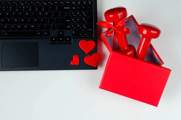 两个红色哑铃 带蝴蝶结在打开的红色盒子 笔记本电脑和心脏白色背景 情人节的概念 网上购物 健康的生活方式 热爱运动 — 图库照片