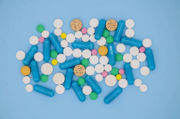 Bir sürü renkli ilaç, mavi arka planda fotokopi alanı olan kapsüller. Çok renkli tıbbi kapsüllerin ve tabletlerin geçmişi. Tıbbi Düzen.