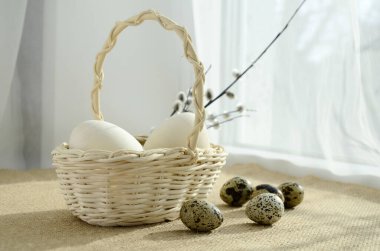 eggs in a white wicker basket and pussy willow branches on windowsill with copy space. Happy Easter concept, Easter table.