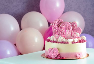 10 numaralı pembe ve beyaz pasta ve masada balonlu kalpler. Doğum günü.