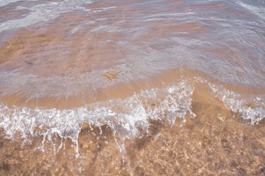 Su sıçratan küçük bir dalga. Su ve kum. Yaz tatili