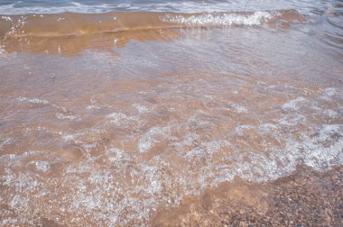 Kıyıdaki küçük dalgalar. Su ve kum dokusu