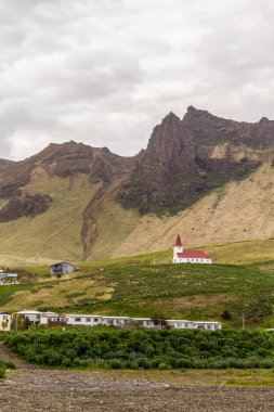Vik i Myrdal 'da kırmızı çatılı kilise, arka planda dağlar, İzlanda