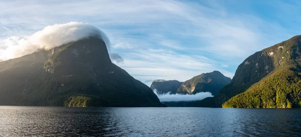 太陽は疑い深い音の上に昇る雲は山の上に低くぶら下がっているニュージーランドの南の島 — ストック写真