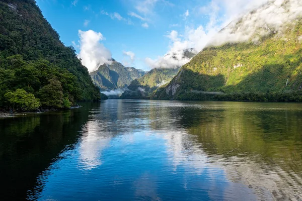 A new morning dawning at Doutful Sound, clouds hanging low in the mountains, South Island of New Zealand