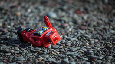 Retro red robot fallen over on rocks clipart