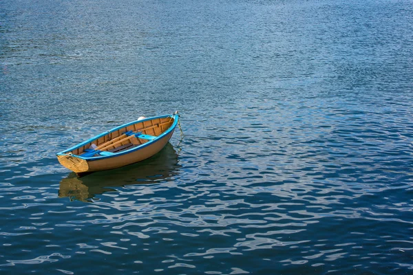 A small row boat sitting calmly in a harbor — Stock Photo, Image