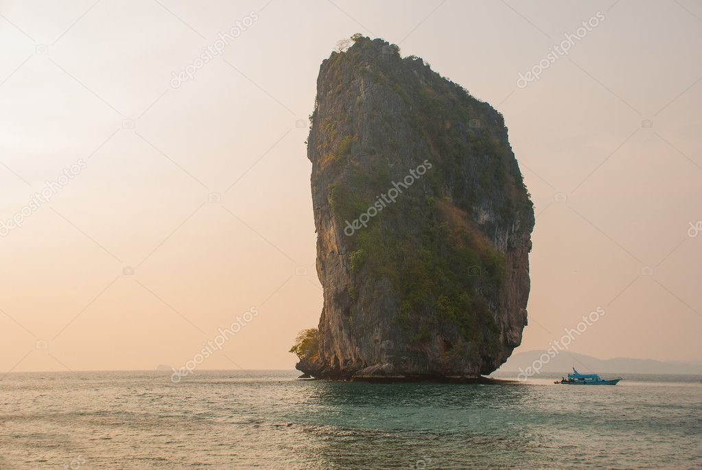 Long tail boat on tropical beach with limestone rock. Sunset, island Taming. Krabi, Thailand.