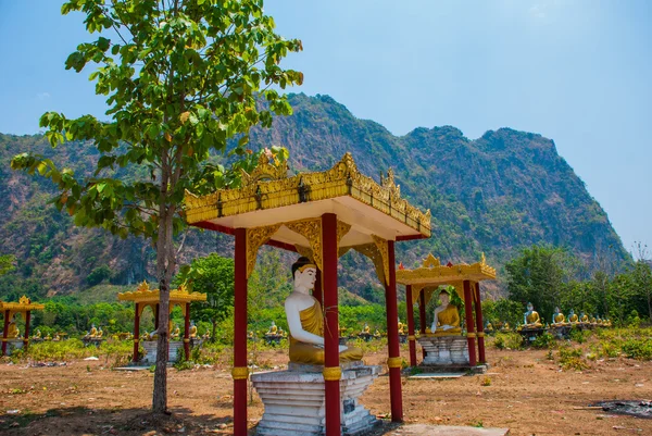 Mnoho soch Buddhů, kteří sedí uprostřed krásné krajiny s horami v slunečný den. HPa-An, Myanmar. Barma. — Stock fotografie