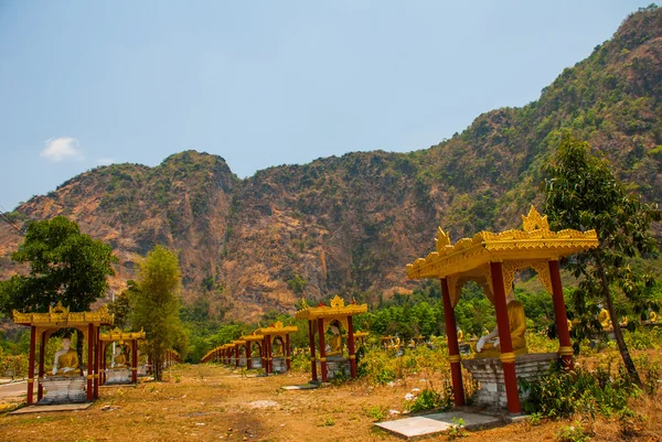 Muitas estátuas dos Budas que se sentam, em meio à bela paisagem com montanhas no dia ensolarado. Hpa-An, Myanmar. Birmânia . — Fotografia de Stock