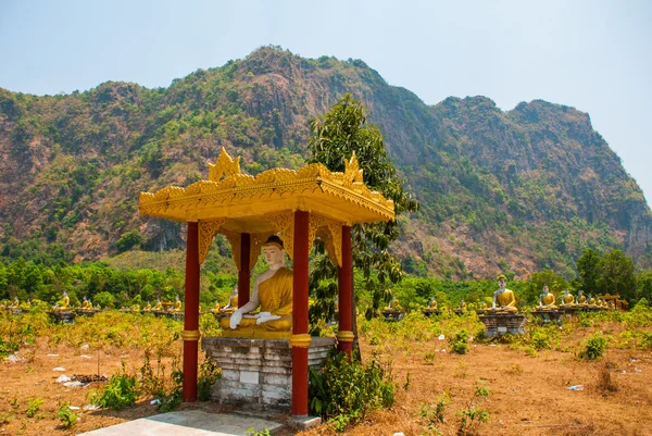 Mnoho soch Buddhů, kteří sedí uprostřed krásné krajiny s horami v slunečný den. HPa-An, Myanmar. Barma. — Stock fotografie