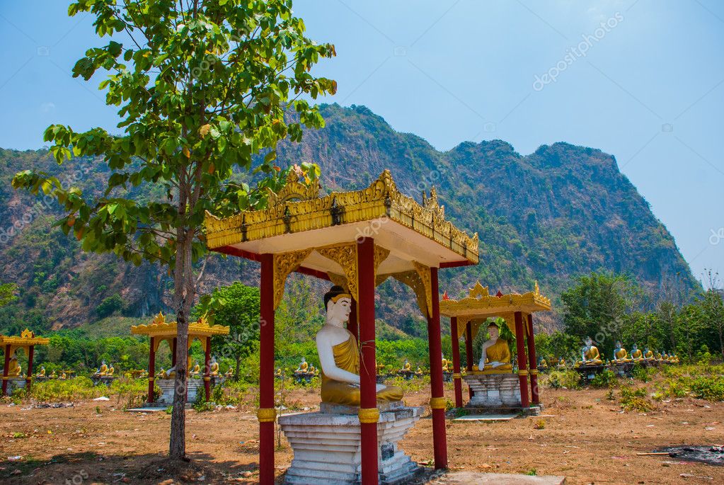 Muchas estatuas de los Budas que se sientan, en medio del hermoso