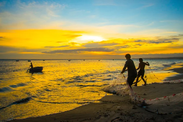 Fishermen at sunset in Vietnam. Men fish with nets, remove the fish from the sea. — Stock Photo, Image