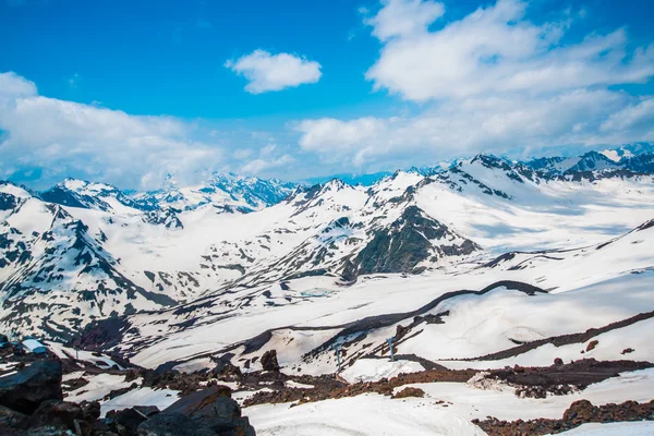 Neve sulle montagne contro il cielo blu nelle nuvole.La regione dell'Elbrus. . — Foto Stock