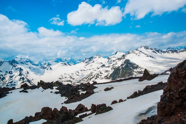 Sníh na horách proti modré obloze v oblacích. Elbrus region. Kavkaz. — Stock fotografie