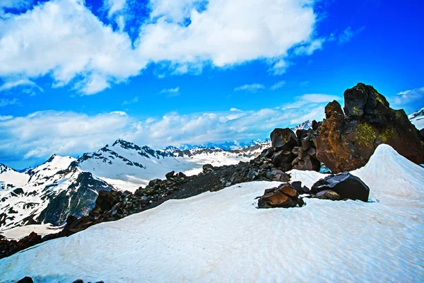 Sníh na horách proti modré obloze v oblacích. Elbrus region. Kavkaz. — Stock fotografie
