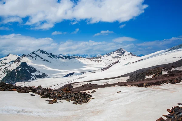 Snö på bergen mot den blå himlen i molnen. Elbrus regionen. Kaukasus. — Stockfoto