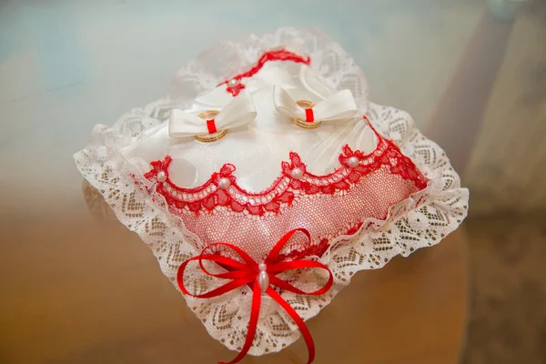 Dos anillos de boda se encuentran en un encaje de almohada rectangular . — Foto de Stock