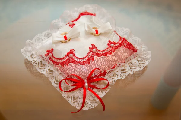 Dos anillos de boda se encuentran en un encaje de almohada rectangular . — Foto de Stock