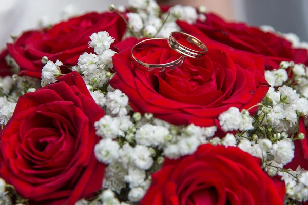 Anéis de noivado e buquê nupcial de rosas vermelhas . — Fotografia de Stock