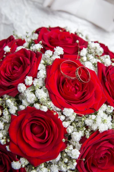 Engagement rings and Bridal bouquet of red roses. Stock Image