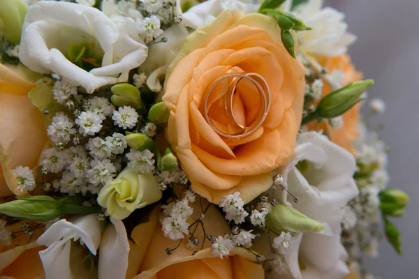 Zwei schöne Eheringe liegen auf einer Untertasse mit Blumen. — Stockfoto