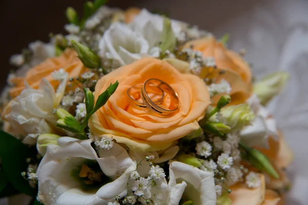 Twee prachtige gouden trouwringen lig op een schoteltje met bloemen. — Stockfoto