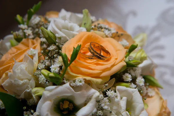 Zwei wunderschöne goldene Trauringe liegen auf einer Untertasse mit Blumen. — Stockfoto