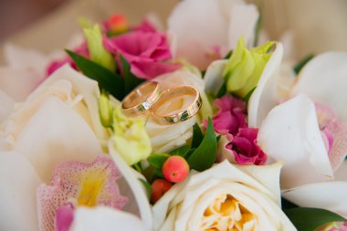 İki altın düğün beyaz orkide ve pembe çiçekler gelinin buket üzerinde yalan bir elmas yüzük.
