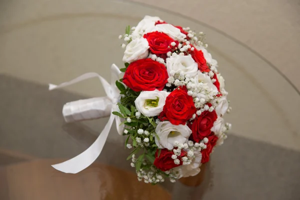 Bukiet ślubny z czerwonych i białych róż leżącego na stole. — Zdjęcie stockowe