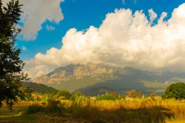 KEMER, TURKEY: dağlarda güzel manzara. Mavi gökyüzüne ve bulutlara karşı dağların güzel manzarası. Yumuşak güneş ışığı dağın tepelerine düşer. Kemer, Türkiye.