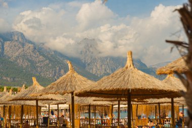 KEMER, TURKEY: Türkiye 'nin Kemer ilinin merkez plajındaki palmiye ağacından yapılmış plaj şemsiyeleri.
